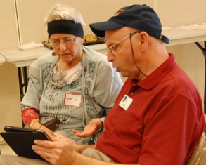 Jim helping another paricipant on a tablet