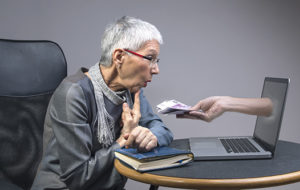 Woman looking at computer screen that has a hand with money coming out of the screen